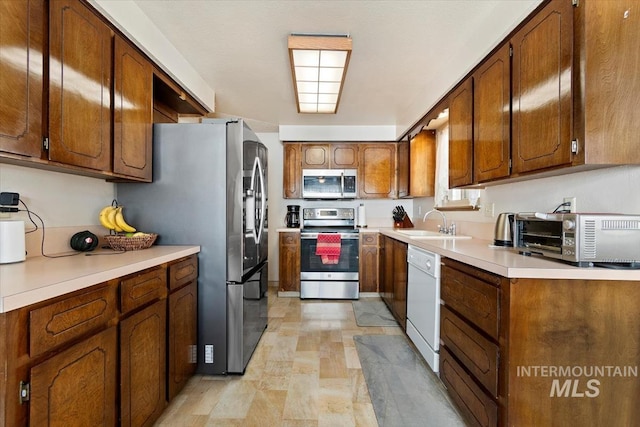 kitchen with a toaster, light countertops, brown cabinets, appliances with stainless steel finishes, and a sink