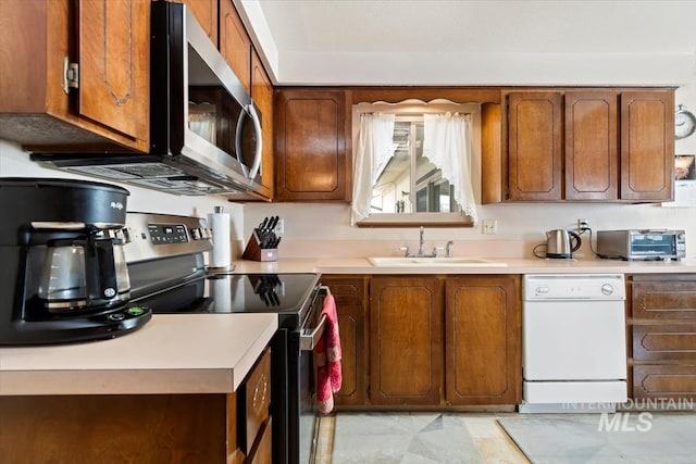 kitchen with a toaster, light countertops, brown cabinets, appliances with stainless steel finishes, and a sink