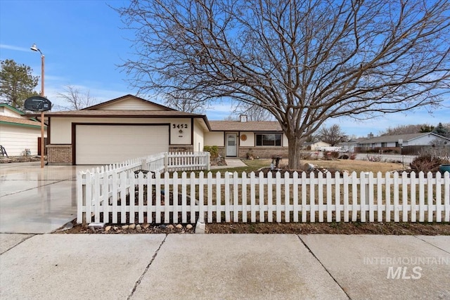 ranch-style house featuring an attached garage, brick siding, driveway, and a fenced front yard