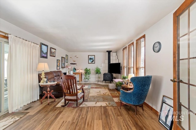 sitting room featuring a wood stove, wood finished floors, and visible vents