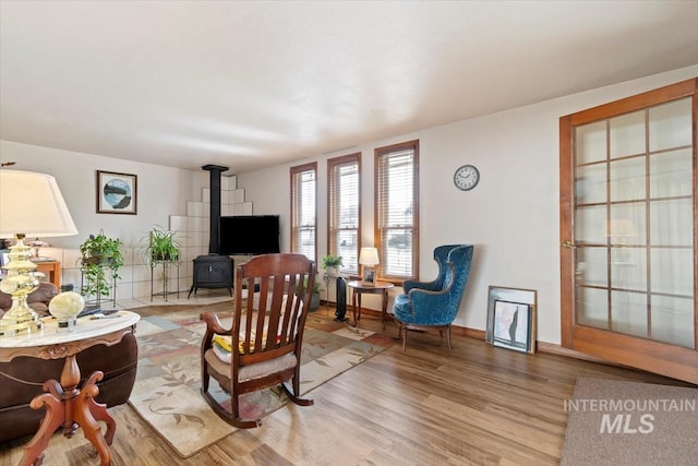 living area with a wood stove, wood finished floors, and baseboards