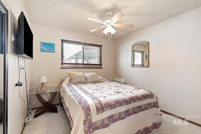 bedroom with baseboards, light carpet, a textured ceiling, and a ceiling fan