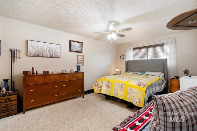 bedroom with light colored carpet, ceiling fan, and a textured ceiling