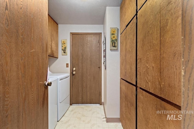 laundry area with cabinet space, a textured ceiling, and washing machine and dryer