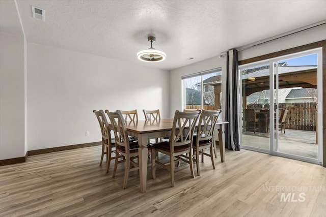 dining area with hardwood / wood-style floors and a textured ceiling