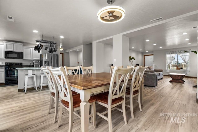 dining area featuring a textured ceiling and light hardwood / wood-style floors