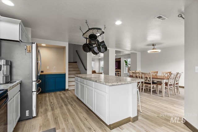 kitchen featuring white cabinets, a kitchen breakfast bar, blue cabinets, light hardwood / wood-style flooring, and a kitchen island