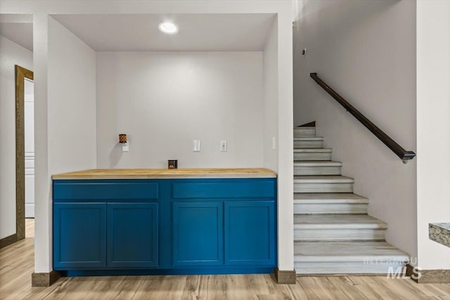 bar featuring blue cabinetry and light hardwood / wood-style flooring