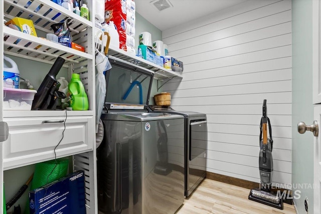 washroom featuring light hardwood / wood-style floors, independent washer and dryer, and wooden walls