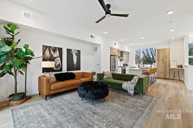 living room featuring light wood-style floors, visible vents, and recessed lighting