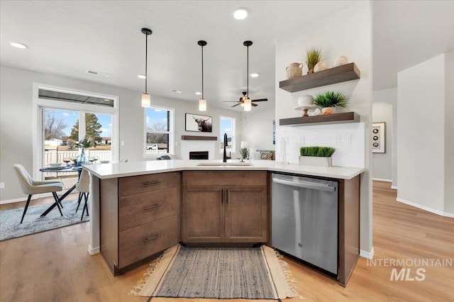 kitchen with stainless steel dishwasher, ceiling fan, light wood-type flooring, and sink