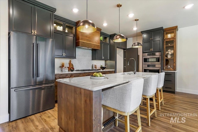 3160 Crescent Moon Rd, Twin Falls, ID 83301 - kitchen with appliances with stainless steel finishes, light stone counters, tasteful backsplash, a center island with sink, and a breakfast bar