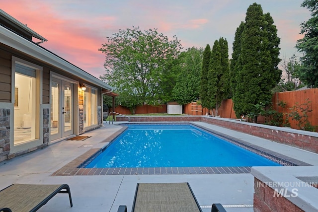7913 W War Bonnet Dr, Boise, ID 83709 - pool at dusk featuring a fenced backyard, french doors, and a patio