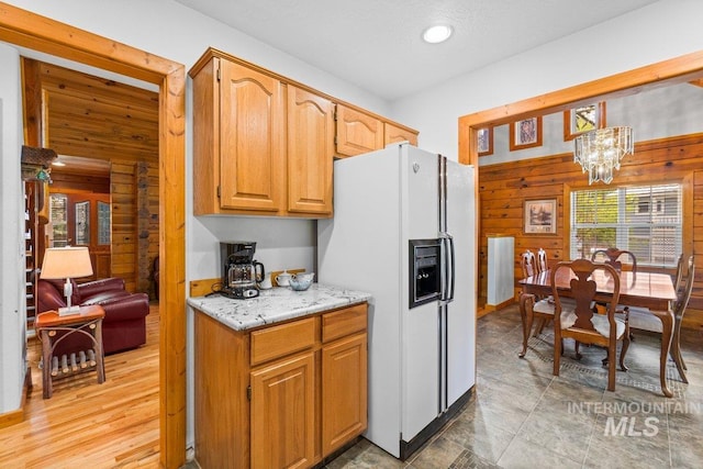14 Sunrise Dr, Garden Valley, ID 83622 - kitchen featuring wood walls, recessed lighting, light stone counters, a notable chandelier, and white fridge with ice dispenser