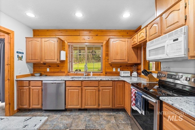 14 Sunrise Dr, Garden Valley, ID 83622 - kitchen with a sink, light stone counters, wooden walls, stainless steel appliances, and recessed lighting