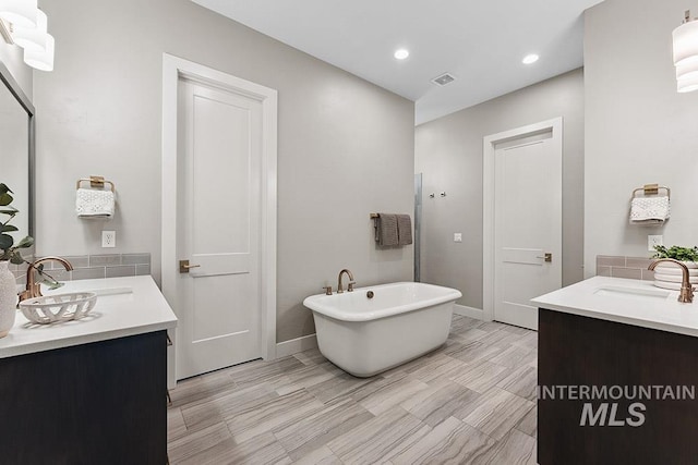 5557 E Hootowl Dr, Boise, ID 83716 - bathroom featuring two vanities, a freestanding bath, baseboards, and recessed lighting