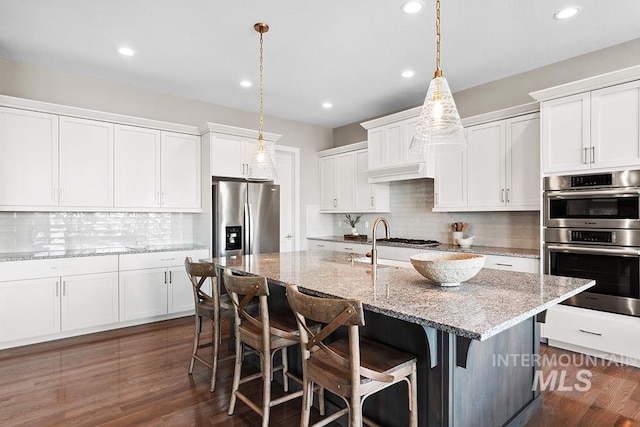 5557 E Hootowl Dr, Boise, ID 83716 - kitchen featuring stainless steel appliances, a breakfast bar, backsplash, and recessed lighting