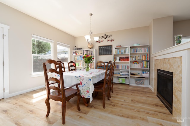 6524 S Derbyshire Ave, Boise, ID 83709 - dining area featuring a chandelier, light wood-type flooring, a tile fireplace, and baseboards