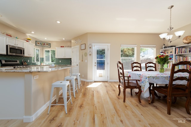 6524 S Derbyshire Ave, Boise, ID 83709 - kitchen featuring stainless steel appliances, a chandelier, light wood-type flooring, white cabinetry, and backsplash