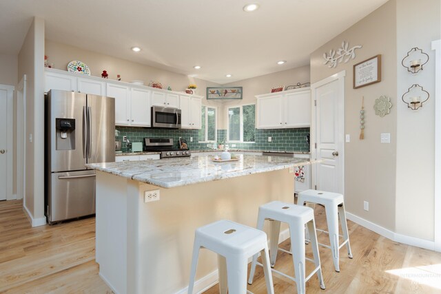 6524 S Derbyshire Ave, Boise, ID 83709 - kitchen featuring appliances with stainless steel finishes, a kitchen island, a breakfast bar area, light wood-type flooring, and tasteful backsplash