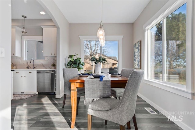 dining space featuring sink, plenty of natural light, and dark wood-type flooring