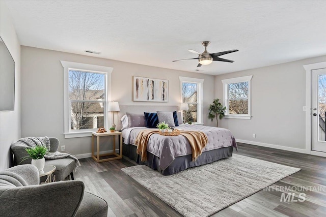 bedroom featuring multiple windows, access to exterior, dark wood-type flooring, and ceiling fan