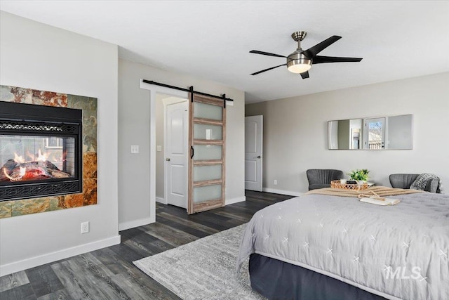 bedroom with ceiling fan, dark wood-type flooring, a multi sided fireplace, and a barn door