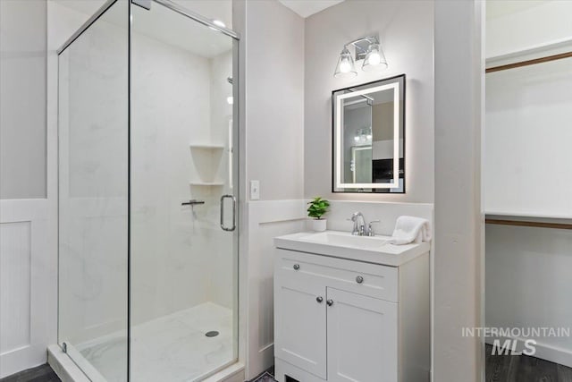 bathroom featuring a shower with door and vanity