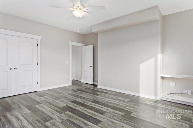 unfurnished bedroom featuring dark hardwood / wood-style floors, a closet, and ceiling fan