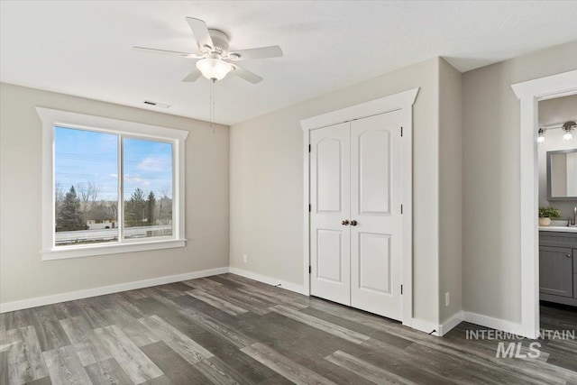 unfurnished bedroom featuring dark hardwood / wood-style flooring, sink, a closet, ceiling fan, and ensuite bathroom