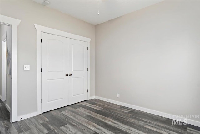 unfurnished bedroom featuring a closet and dark wood-type flooring