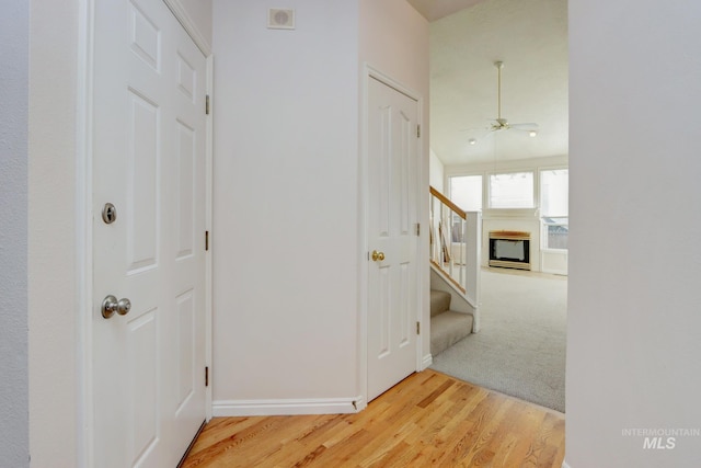 hall with light carpet, baseboards, visible vents, stairs, and light wood-type flooring