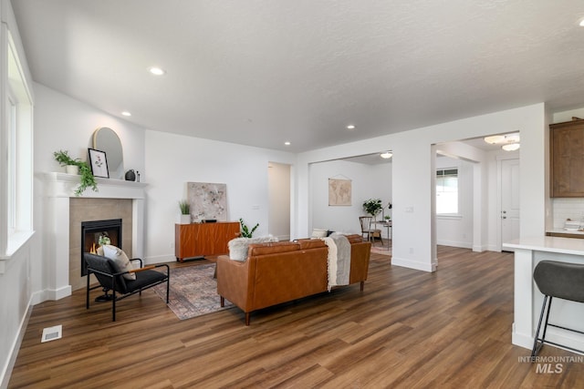 living room featuring dark hardwood / wood-style floors and a tiled fireplace