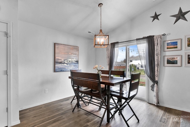 dining room featuring baseboards, visible vents, wood finished floors, and a chandelier