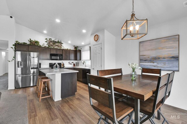 dining room featuring an inviting chandelier, recessed lighting, wood finished floors, lofted ceiling, and visible vents