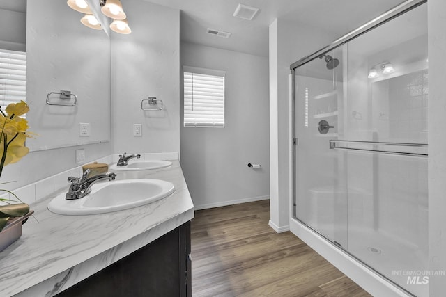 full bathroom featuring visible vents, a sink, a stall shower, and wood finished floors