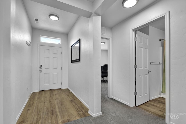 corridor with baseboards, wood finished floors, and visible vents