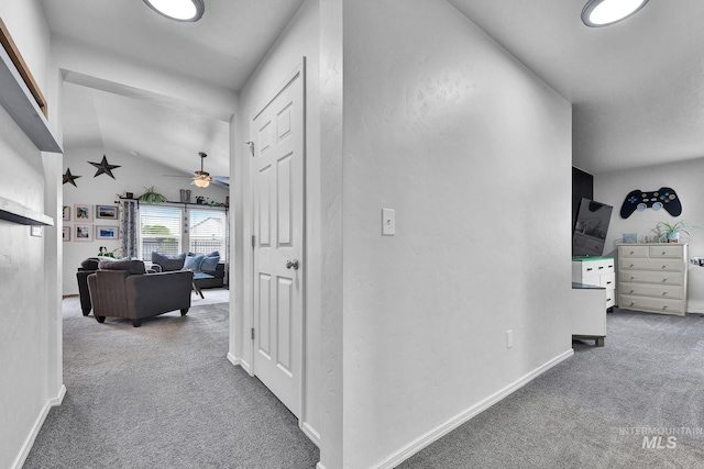 hallway featuring carpet flooring, baseboards, and lofted ceiling