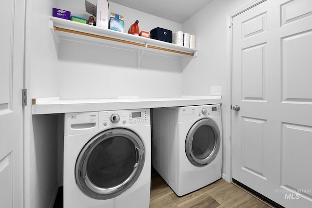 washroom featuring separate washer and dryer, laundry area, and light wood-type flooring