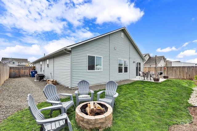 rear view of house featuring a lawn, a fenced backyard, a patio area, and an outdoor fire pit