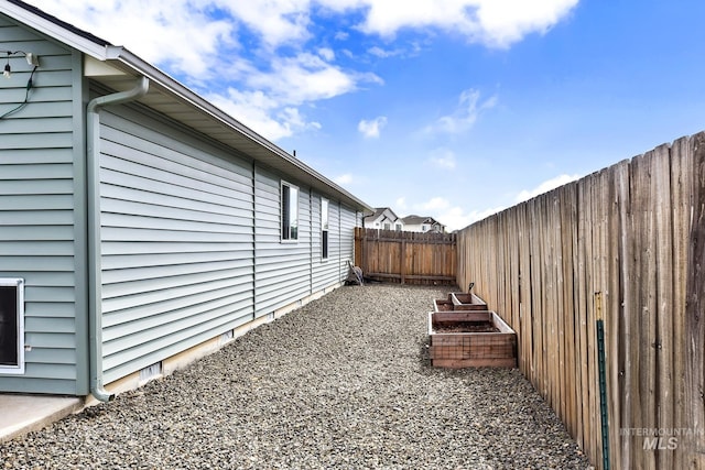 view of property exterior featuring a fenced backyard and a vegetable garden