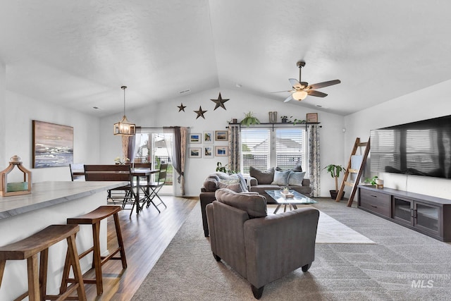 living area featuring a ceiling fan, vaulted ceiling, a healthy amount of sunlight, and wood finished floors