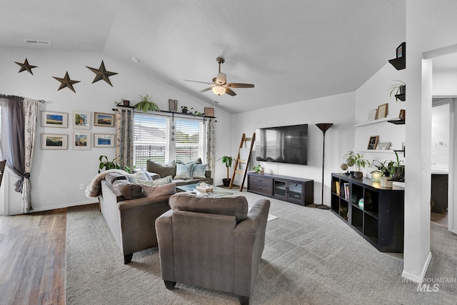 living area with ceiling fan, visible vents, baseboards, wood finished floors, and vaulted ceiling