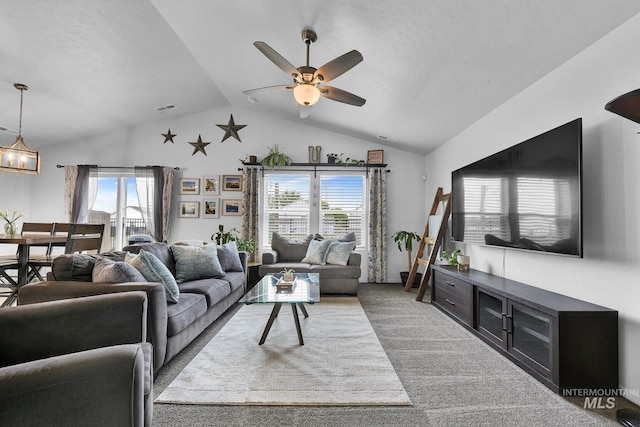 carpeted living room featuring visible vents, ceiling fan with notable chandelier, a healthy amount of sunlight, and high vaulted ceiling