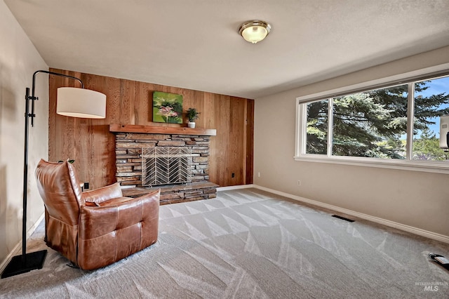 living room featuring wooden walls, visible vents, carpet flooring, and a fireplace