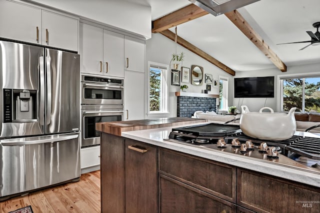 kitchen with dark brown cabinetry, open floor plan, a ceiling fan, beam ceiling, and stainless steel appliances