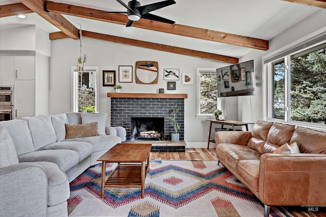 living area with a fireplace, lofted ceiling with beams, a ceiling fan, and a wealth of natural light