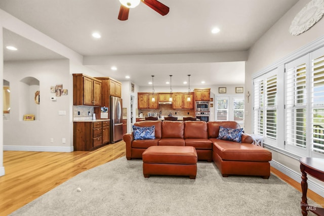 living room with arched walkways, light wood finished floors, recessed lighting, and baseboards