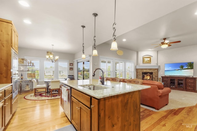 kitchen featuring light wood-type flooring, a fireplace, stainless steel appliances, and a sink