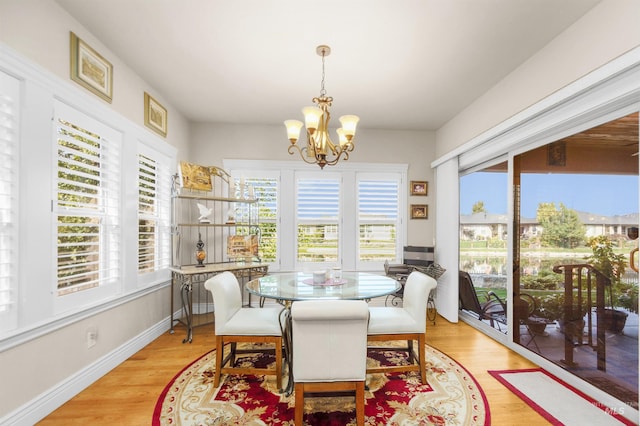 dining room featuring light wood-type flooring, a notable chandelier, and baseboards